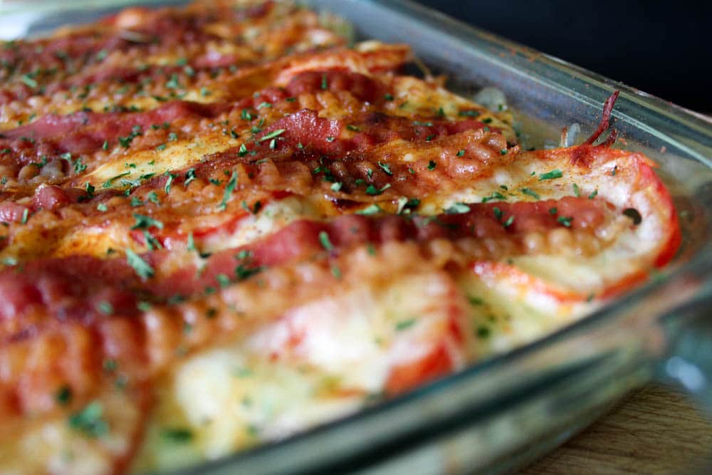 A close up of the top of keto Kentucky hot brown casserole with crispy bacon, chopped fresh parsley and roasted tomatoes. 