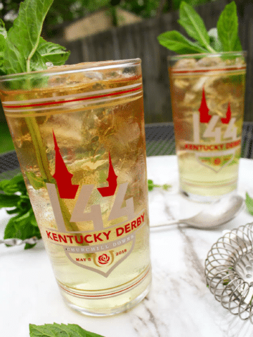 two mint juleps in Kentucky derby glasses
