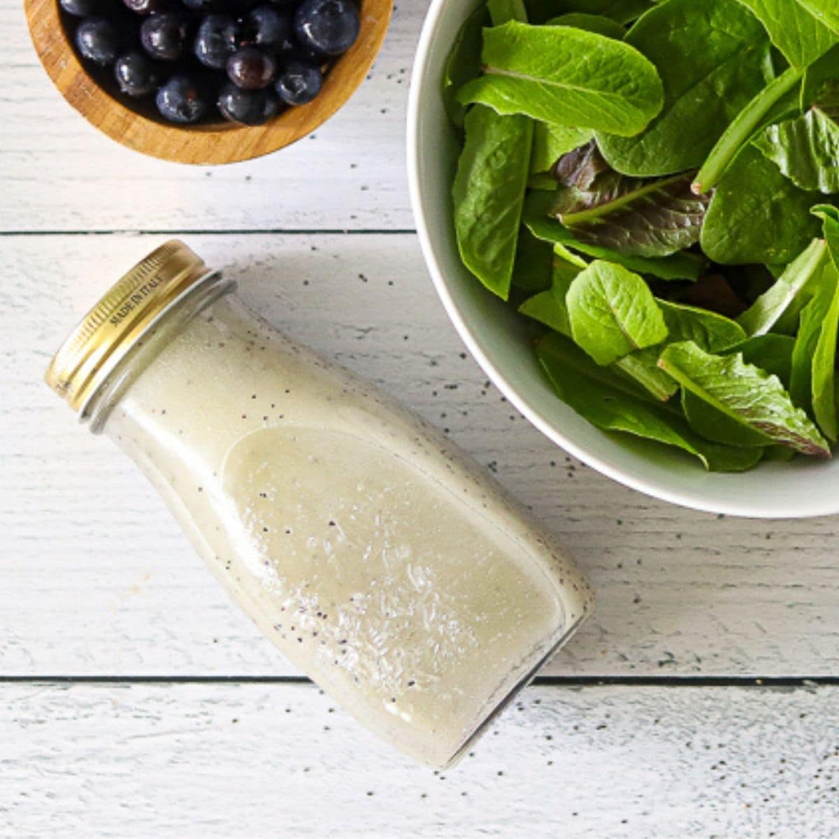sugar free poppyseed dressing in a glass jar next to a bowl of lettuce
