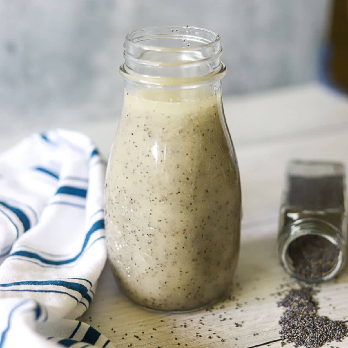 a glass bottle full of sugar free poppyseed dressing with a white background.