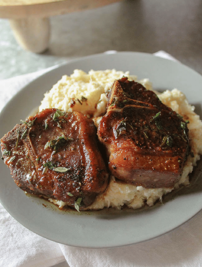 a grey plate with mashed cauliflower topped with two lamb loin chops