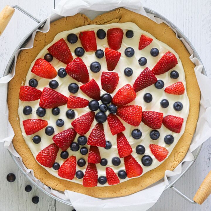an overhead shot of a fruit pizza topped with fresh blueberries and strawberries