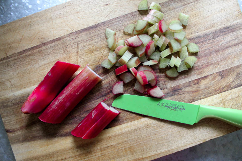 A wooden cutting board with chopped rhubarb stalks