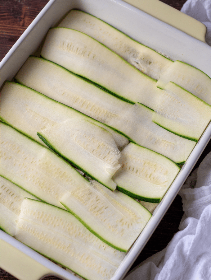 Zucchini slices layered in a casserole dish for a Low Carb Chicken Pesto Lasagna with Zucchini Noodles