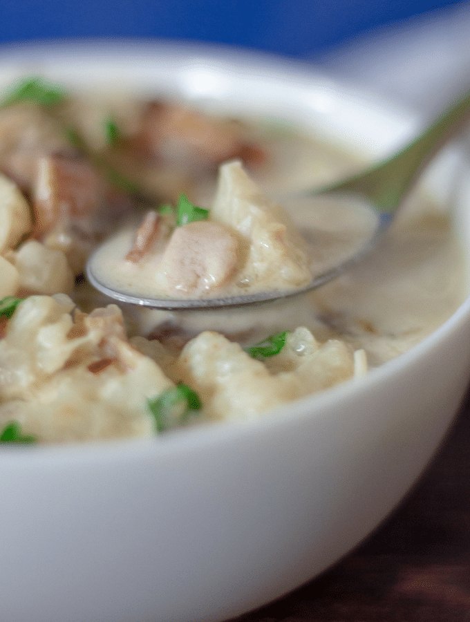a white bowl full of low carb clam chowder made with cauliflower
