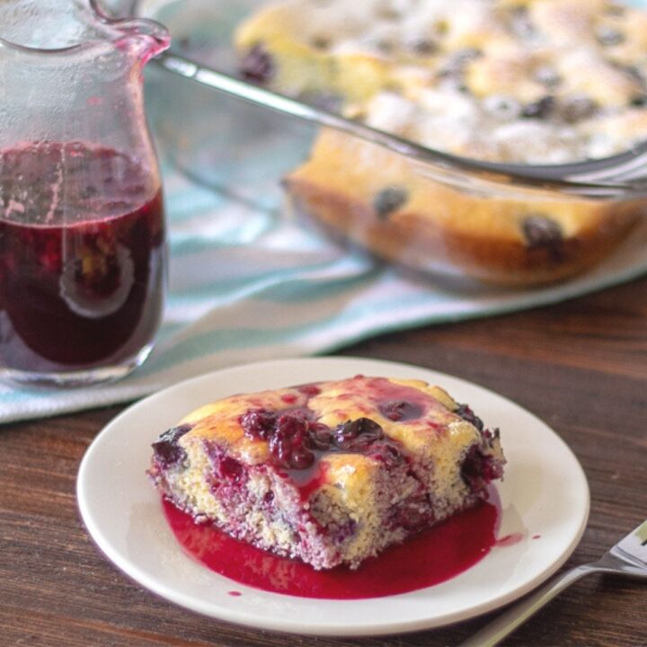 a slice of keto blueberry pancake casserole on a plate topped with blueberry syrup
