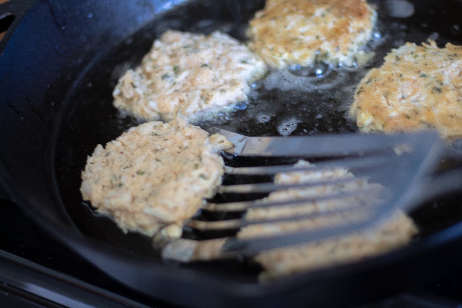 crab cakes cooking in a cast iron skillet