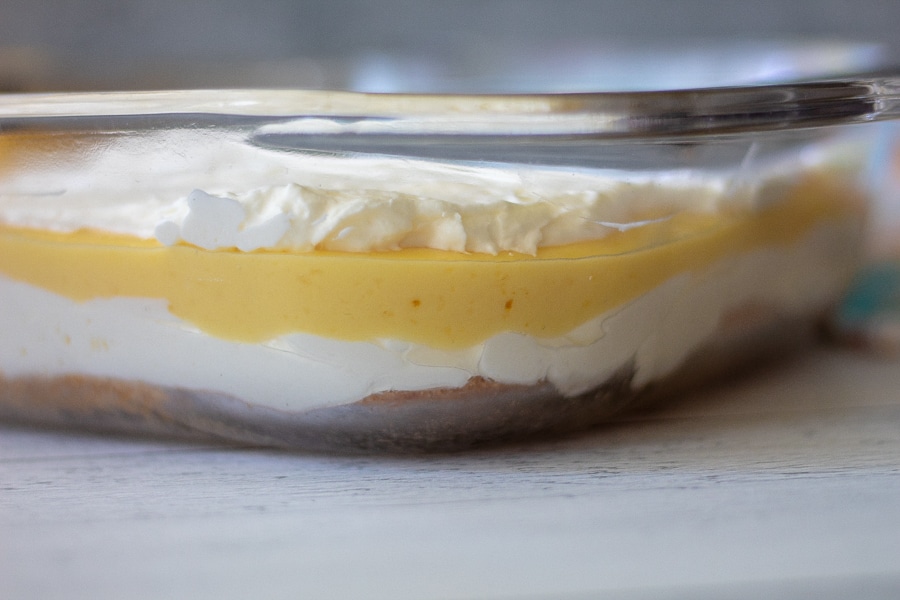 A side view of keto lemon lush dessert with 4 layers in a glass dish
