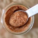 easy homemade taco seasoning in a glass jar with a metal measuring spoon perched on top
