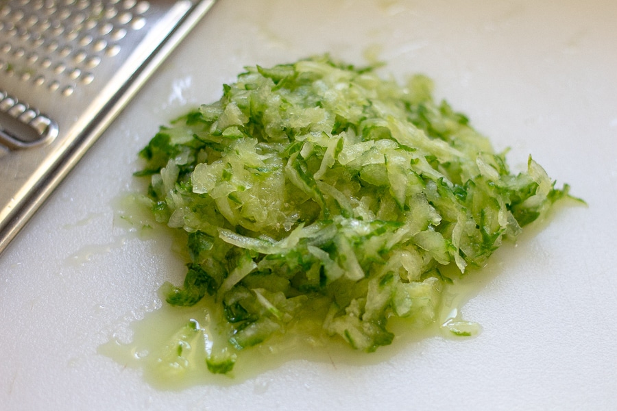 Grated cucumber on a white cutting board in preparation for benedictine 