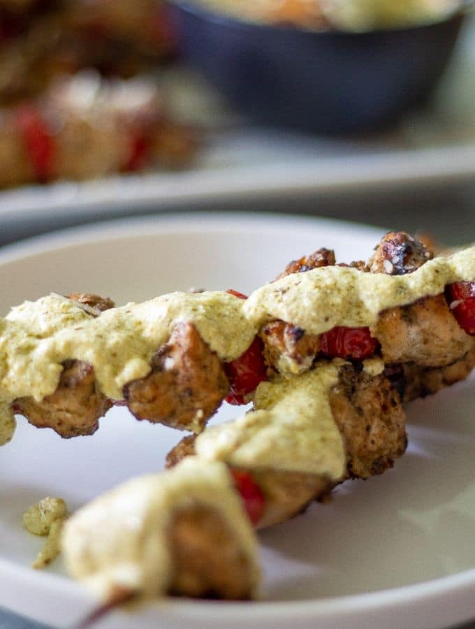 chicken pesto skewers with cherry tomatoes topped with ricotta pesto sauce