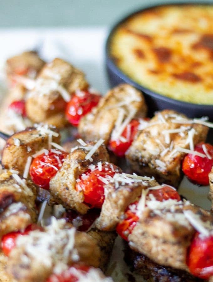 chicken pesto skewers with cherry tomatoes arranged on a serving platter