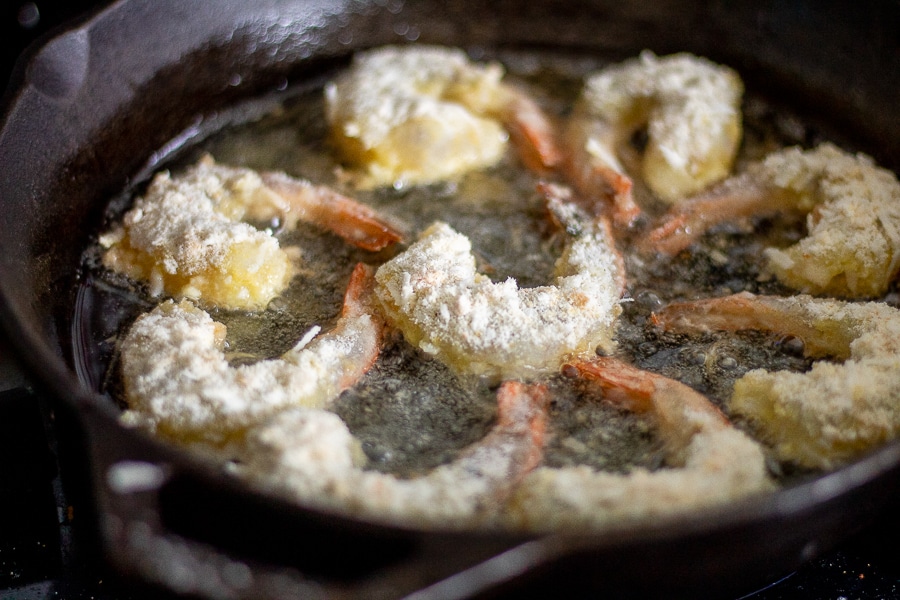 low carb coconut shrimp frying in a cast iron skillet