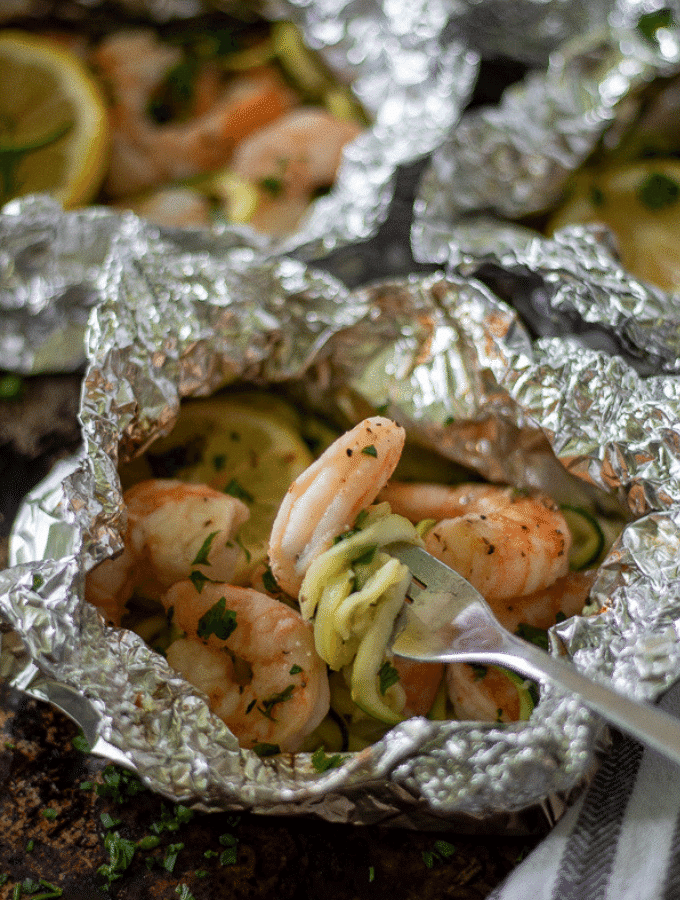 Close up shot of a healthy shrimp foil packet with spiralized zucchini wrapped around a silver fork