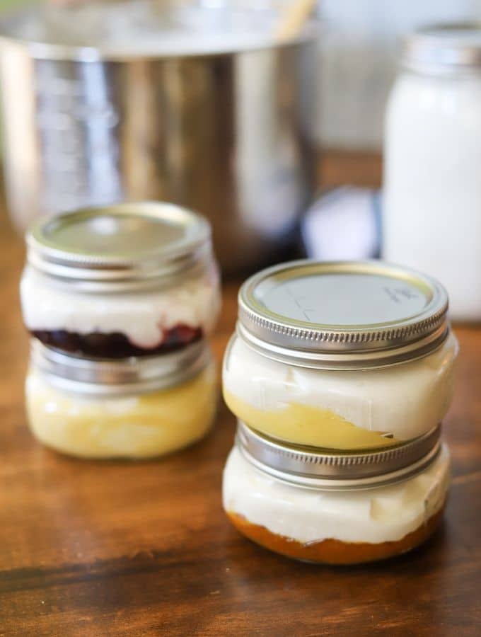 Four small mason jars full of homemade keto yogurt with fruit on the bottom