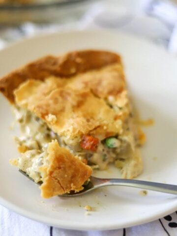 a slice of keto chicken pot pie on a white plate with a flaky crust.