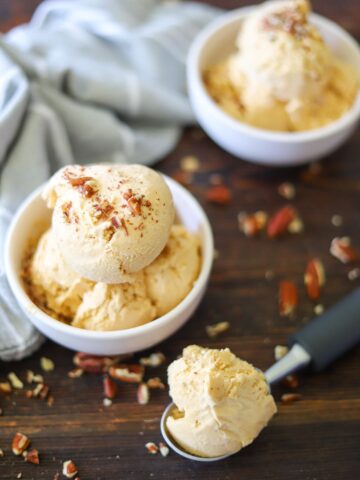 Two white bowls full of sugar free pumpkin ice cream topped with chopped pecans