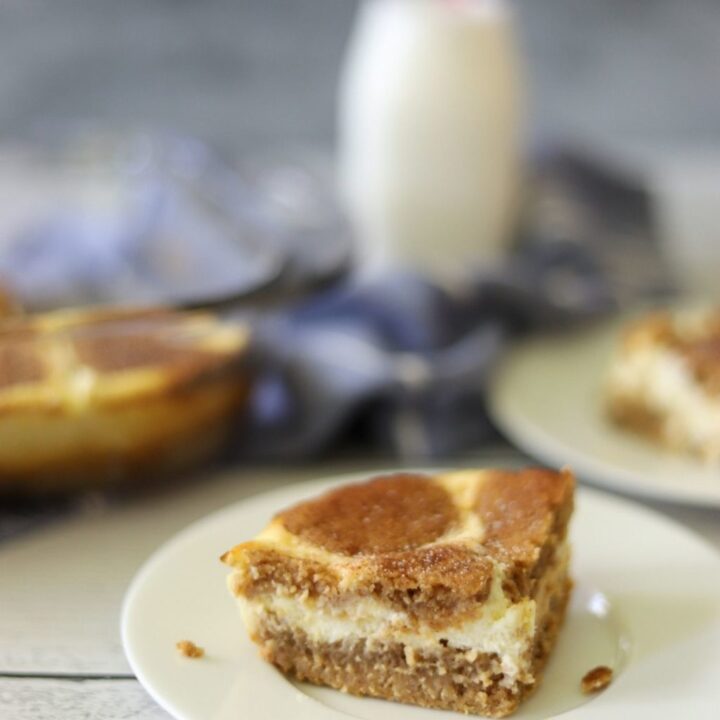 a keto snickerdoodle cheesecake bar on a white plate with a milk bottle in the background