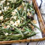 Close up of roasted green beans with almonds on a sheet pan