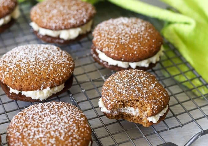 homemade gingerbread whoopie pies on a cooling rack sprinkled with powdered sugar