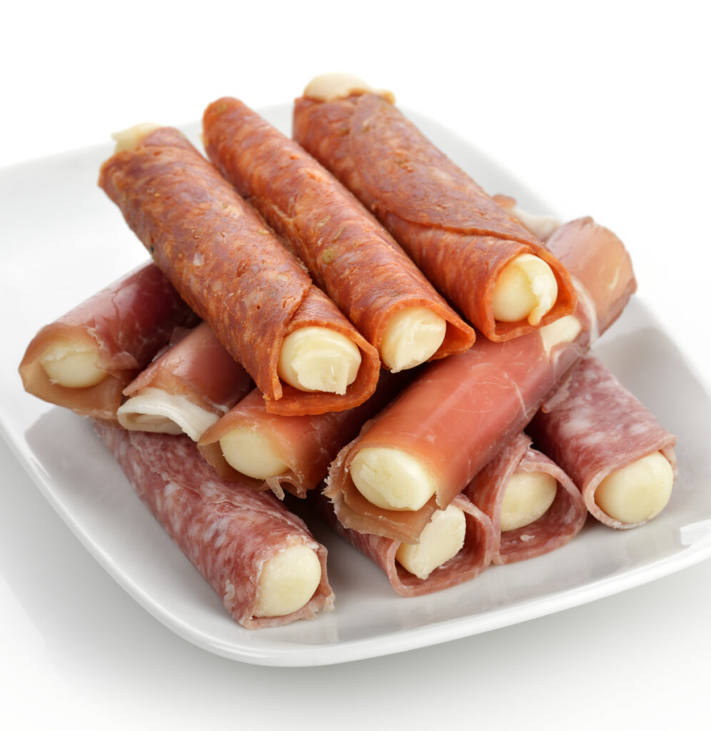 Salami and cheese rolls on a white plate with a white background