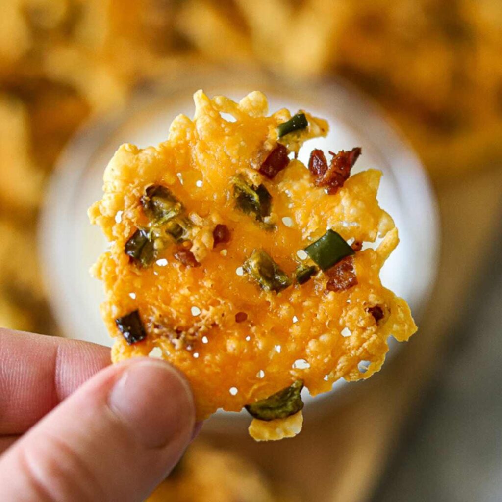 a single jalapeno popper cheese crisp being held up.