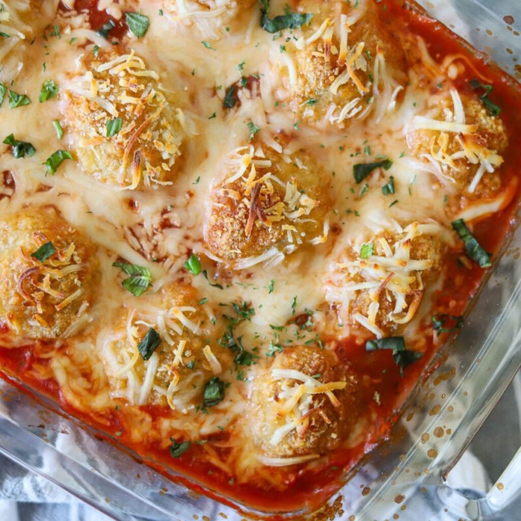 Chicken meatballs in a baking dish with marinara sauce and melted cheese
