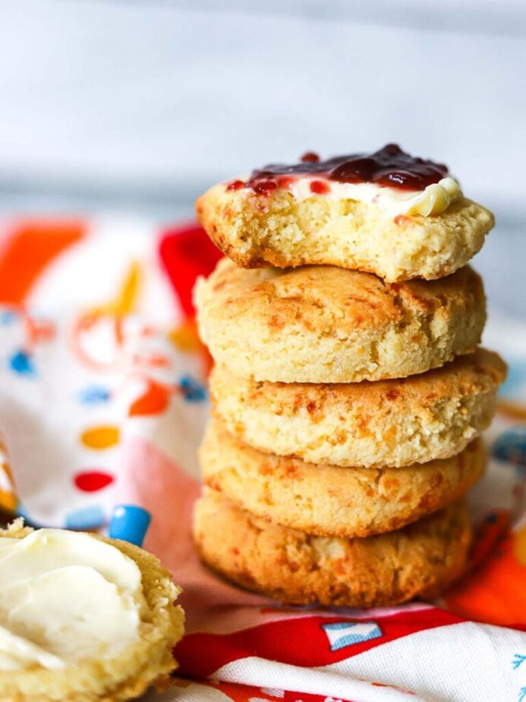 A stack of cooked biscuits, one is smeared with purple jam. 