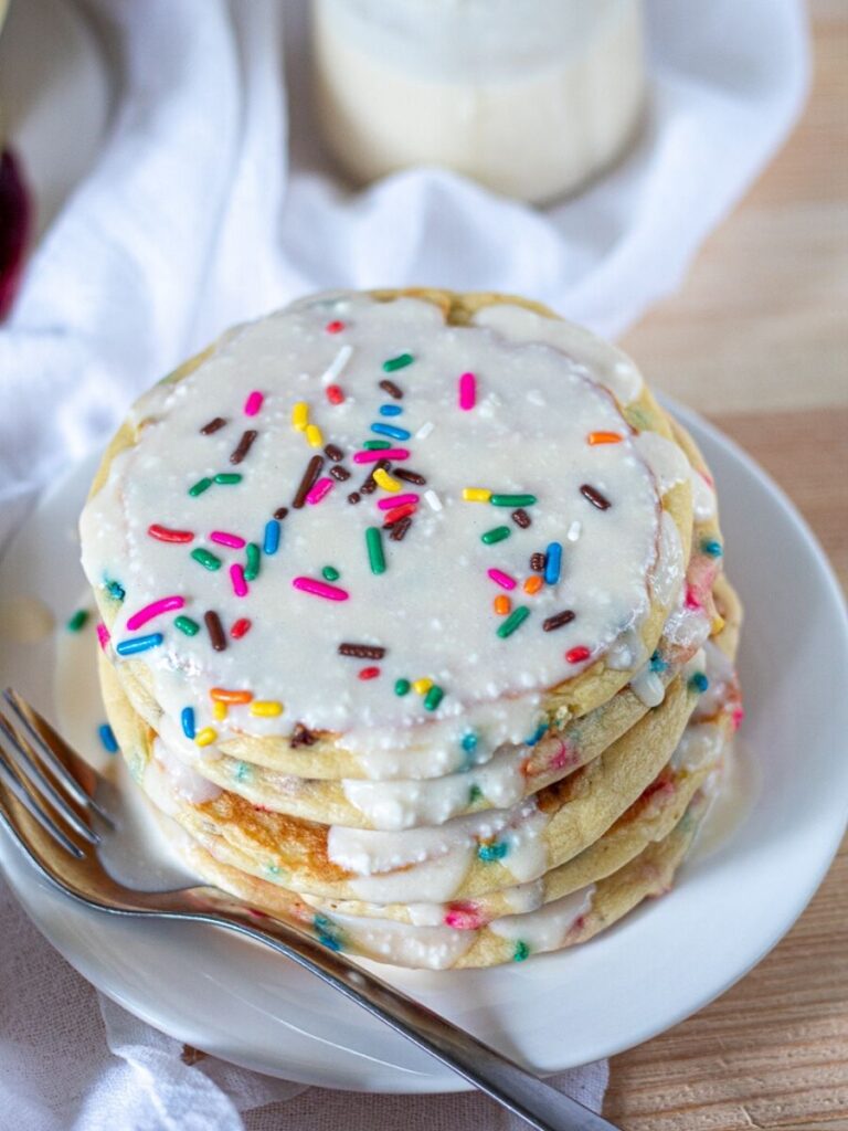 A stack of low carb birthday cake pancakes topped with vanilla frosting syrup!
