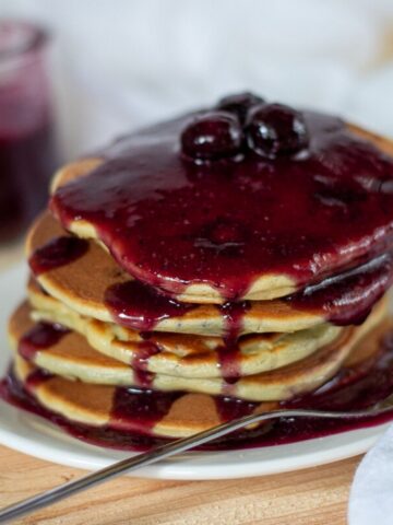 A stack of keto blueberry pancakes topped with a blueberry sauce