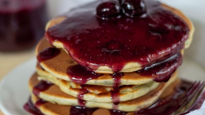 A stack of keto blueberry pancakes topped with a blueberry sauce