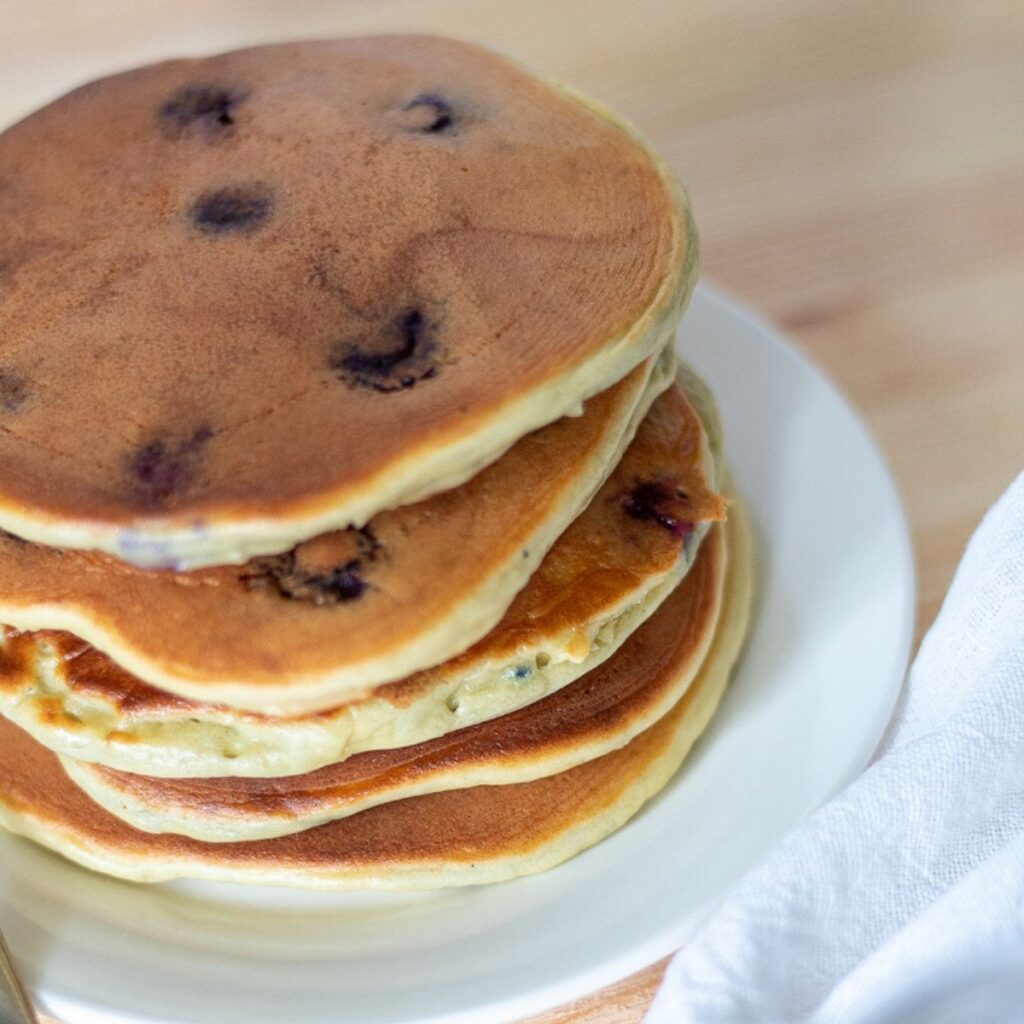 A stack of low carb blueberry pancakes on a white plate