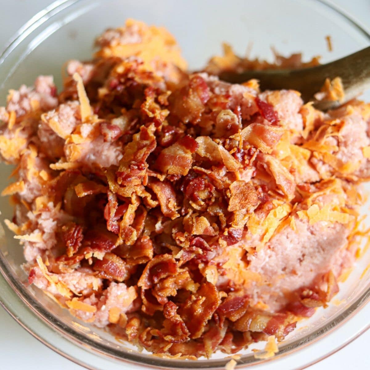 a bowl full of ground turkey, shredded sweet potato, and bacon crumbles.