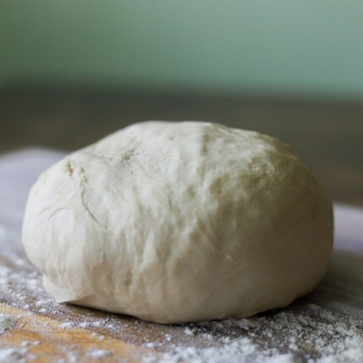 a ball of pizza dough on a floured wooden cutting board