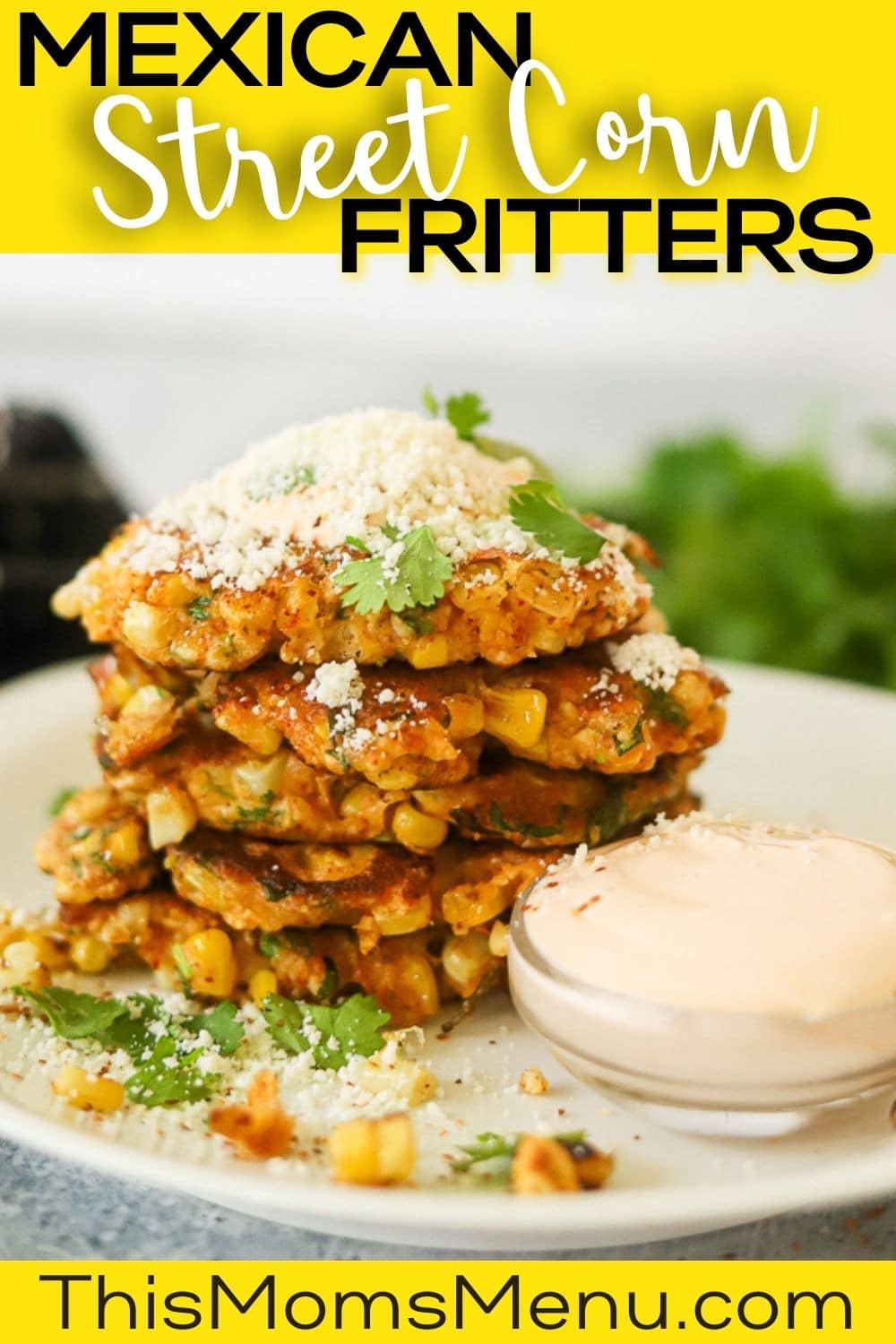 A stack of elote corn fritters on a white plate topped with sour cream and cotija cheese.