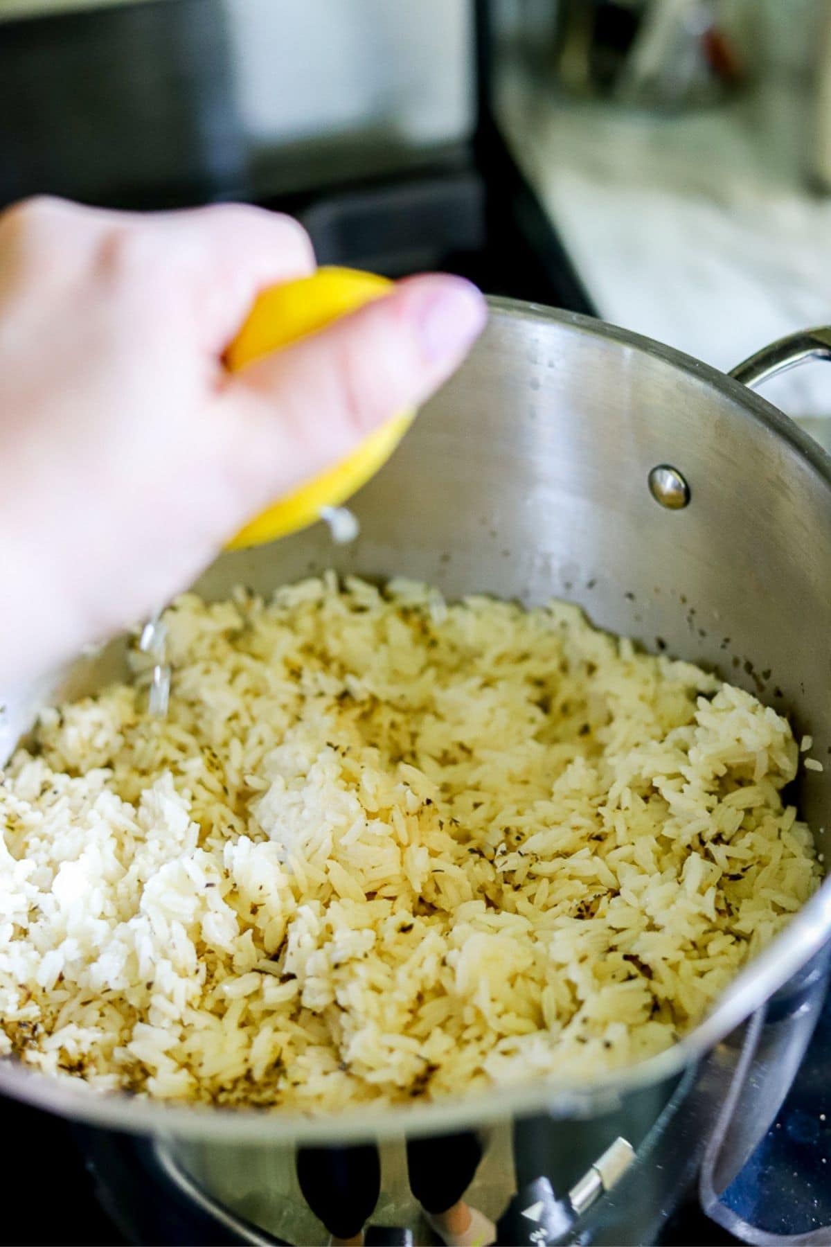 fresh lemon juice being squeezed into a pot of fresh rice.