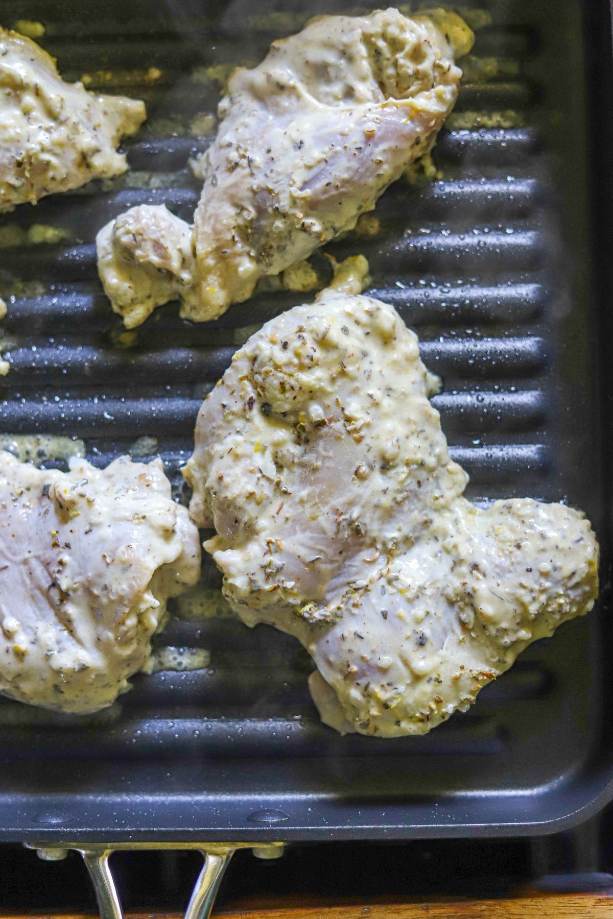 marinated chicken thighs cooking on a grill pan.