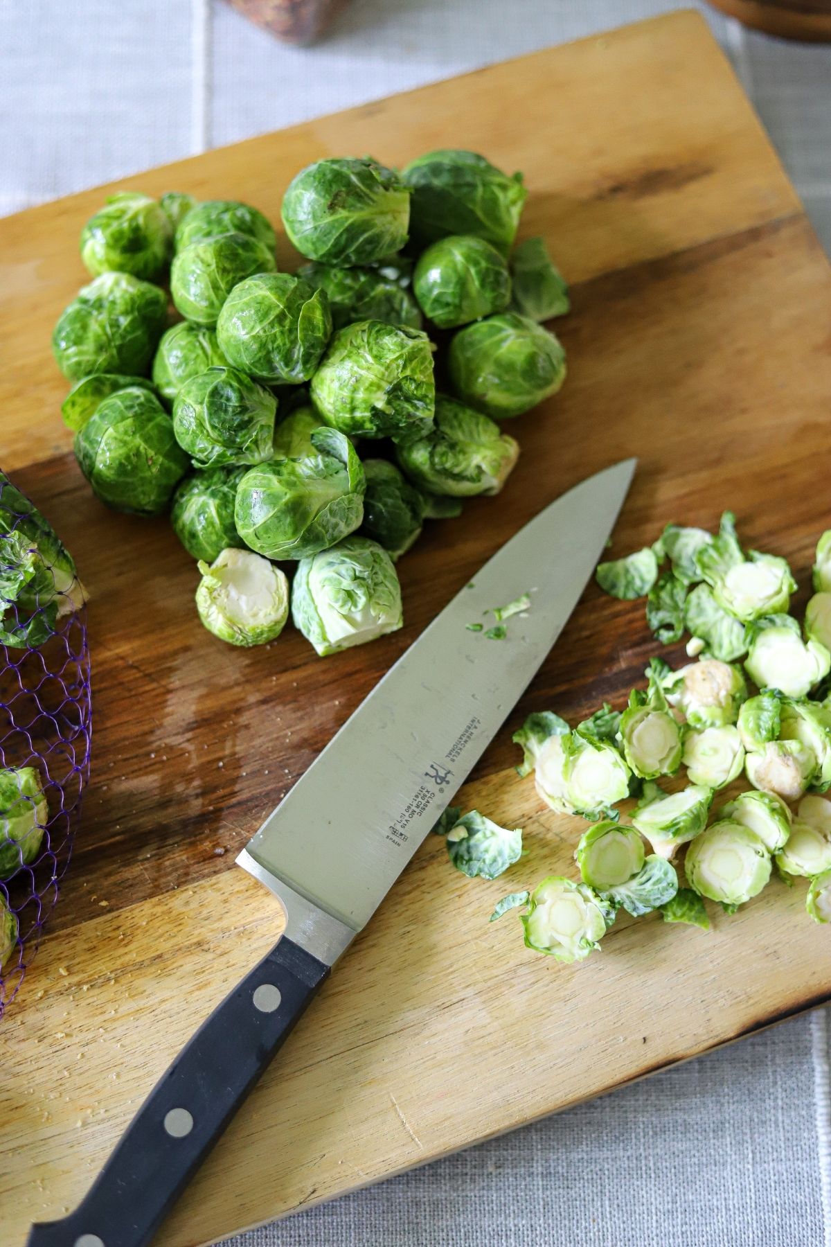brussles sprouts being trimmed on a wooden cutting board 