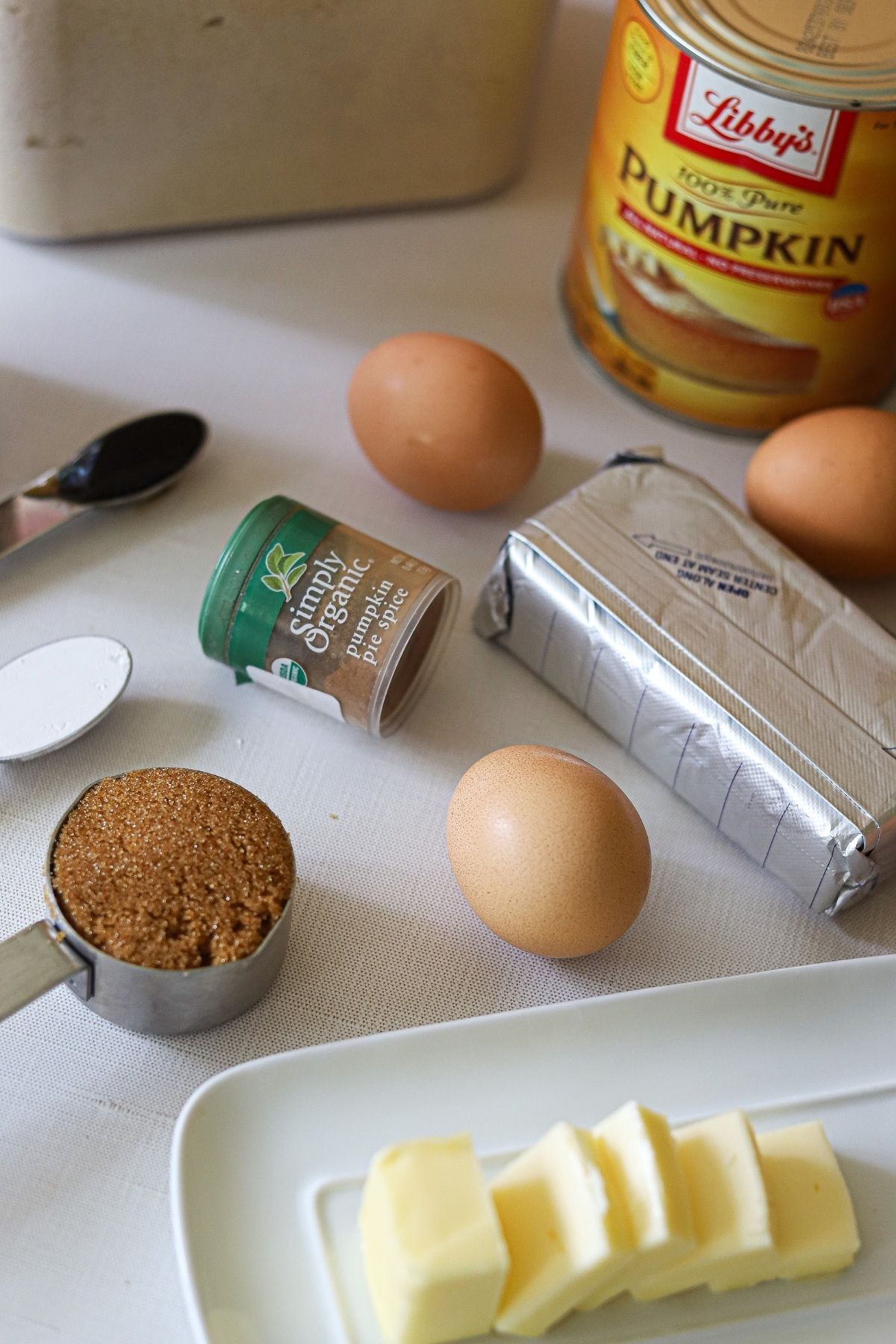 almond flour, pumpkin puree, eggs, vanilla, baking powder, butter, brown sugar substitute, and cream cheese laid out on a counter