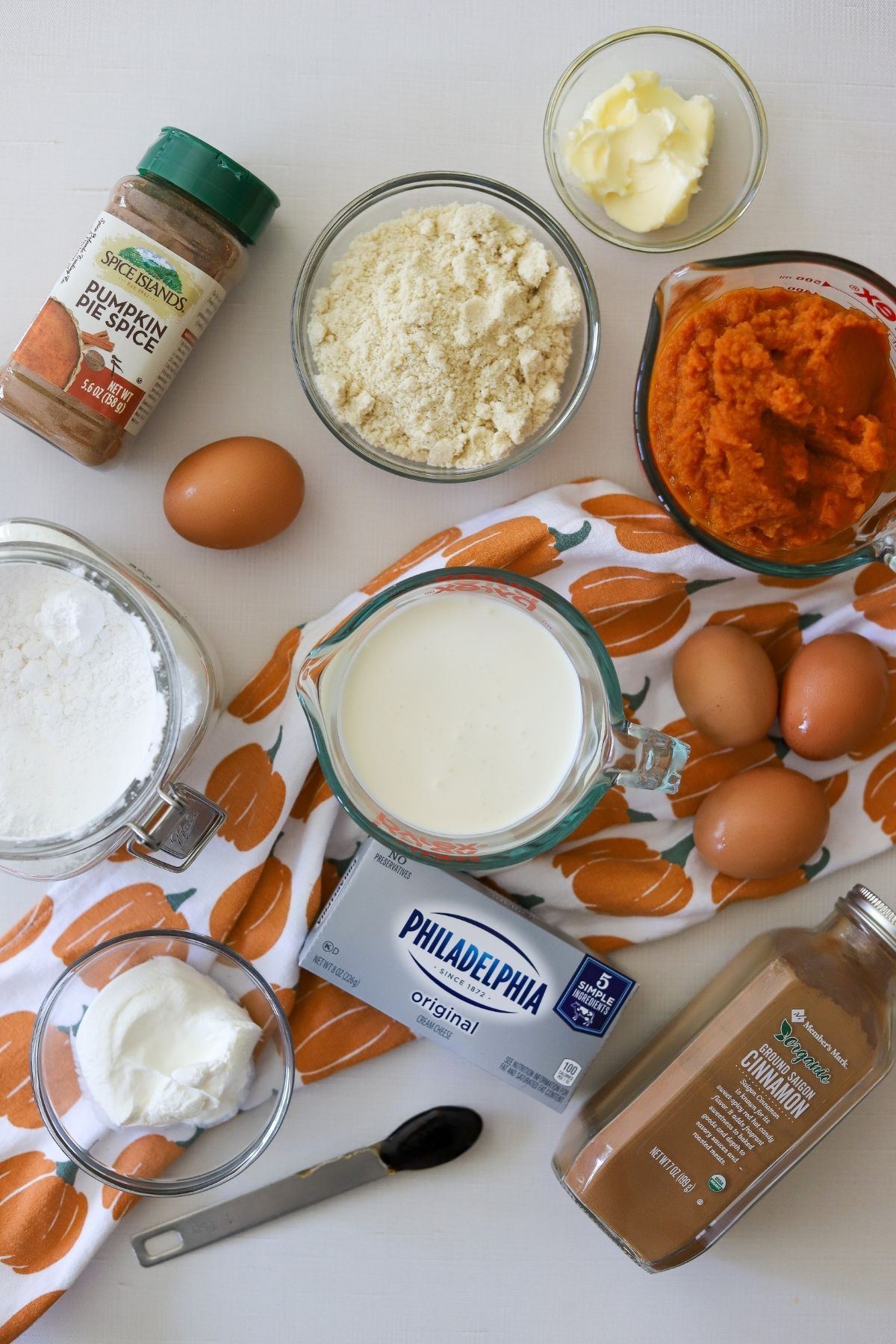 Ingredients for low carb pumpkin cheesecake bars including pumpkin puree, butter, pumpkin pie spice, eggs, cream cheese, vanilla, and sweetener. 