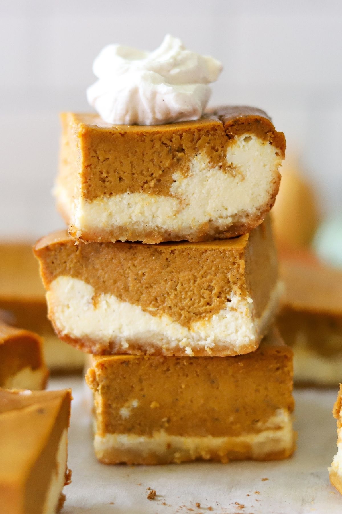 Three pumpkin cheesecake bars stacked on top of each other. 