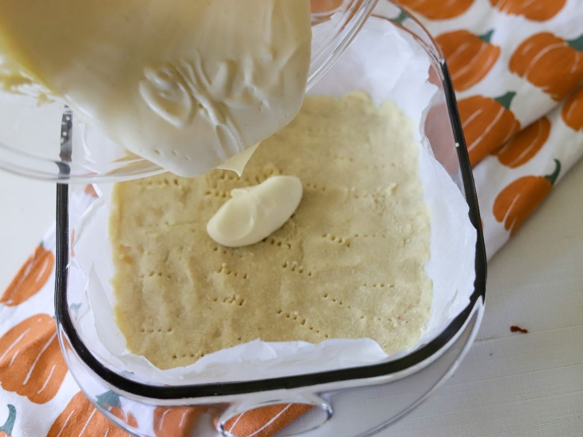 cheesecake batter being poured over an almond flour crust