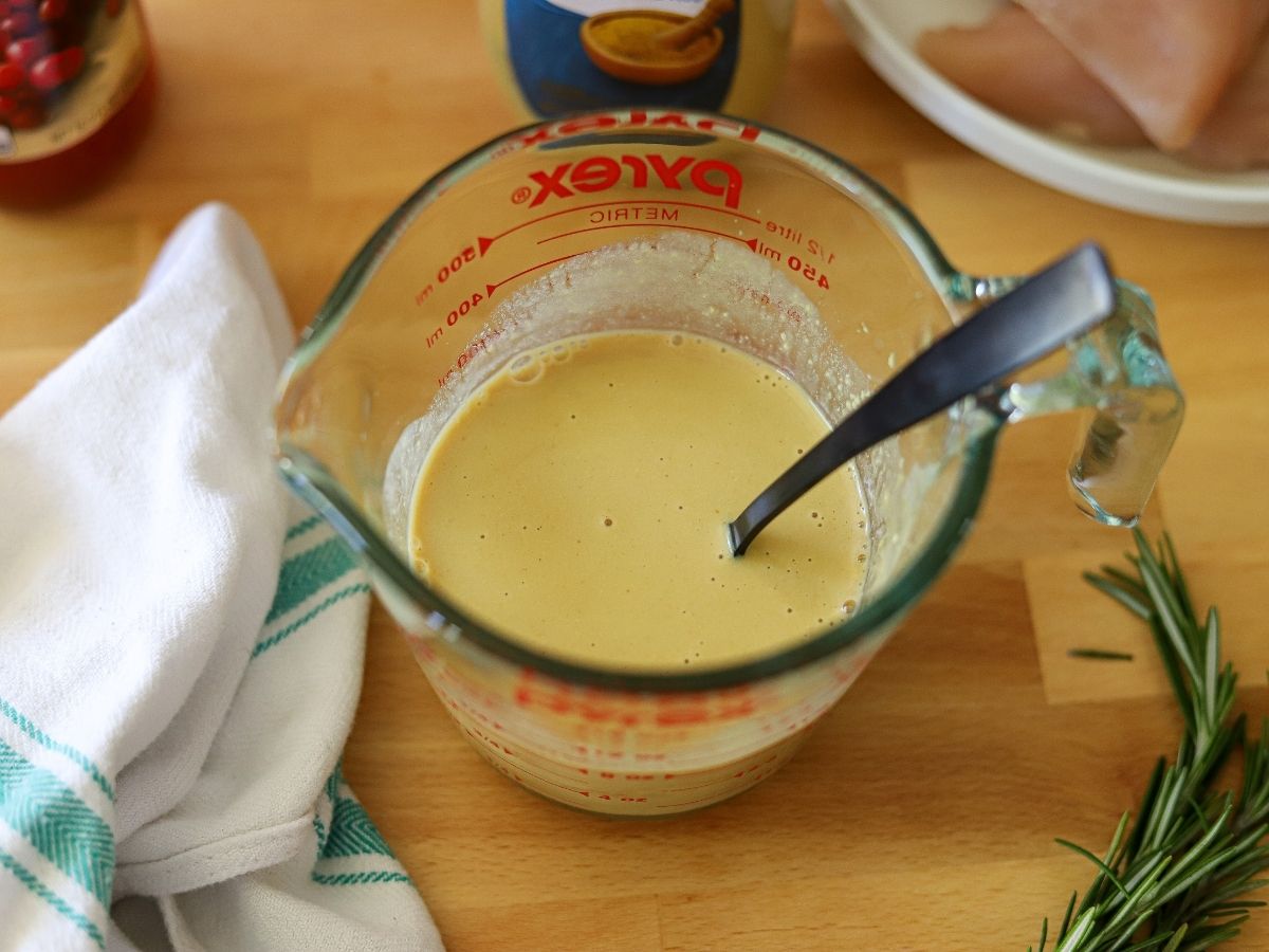 mayonnaise, mustard, maple syrup, and vinegar mixed together in a measuring cup.