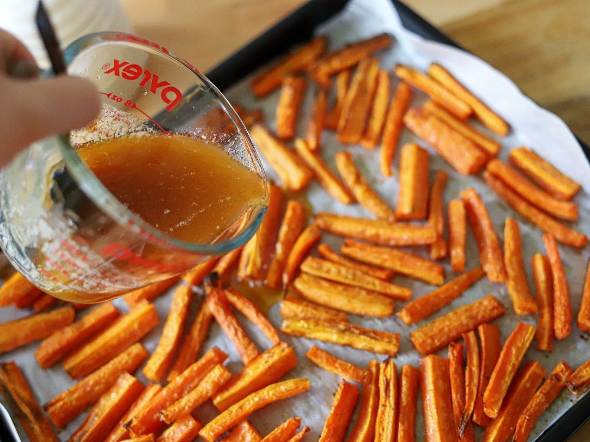 roasted carrots being coated in a honey, butter, and cayenne glaze. 