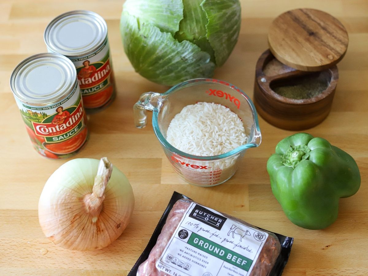 ingredients for cabbage roll casserole inluding cabbage, tomato sauce, onion, ground beef, rice, and green pepper.