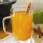 a glass full of warm mulled cider, or wassail, garnished with a cinnamon stick.
