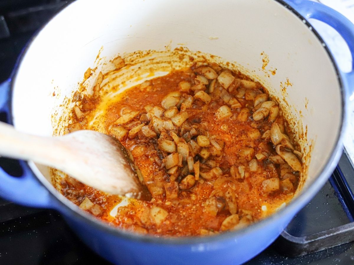 onions, garlic, cumin, and chili powder sautéing in a large pot.