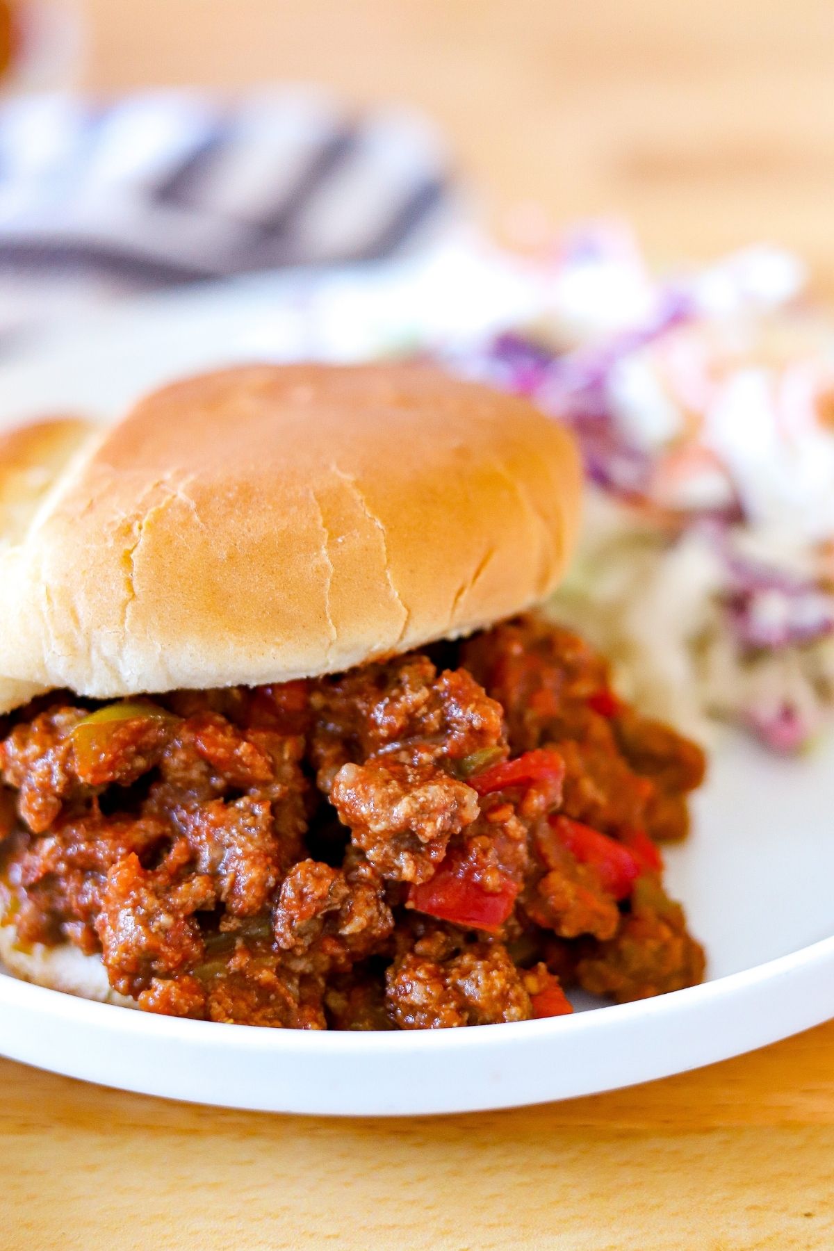A sloppy joe with red and green peppers on a white plate