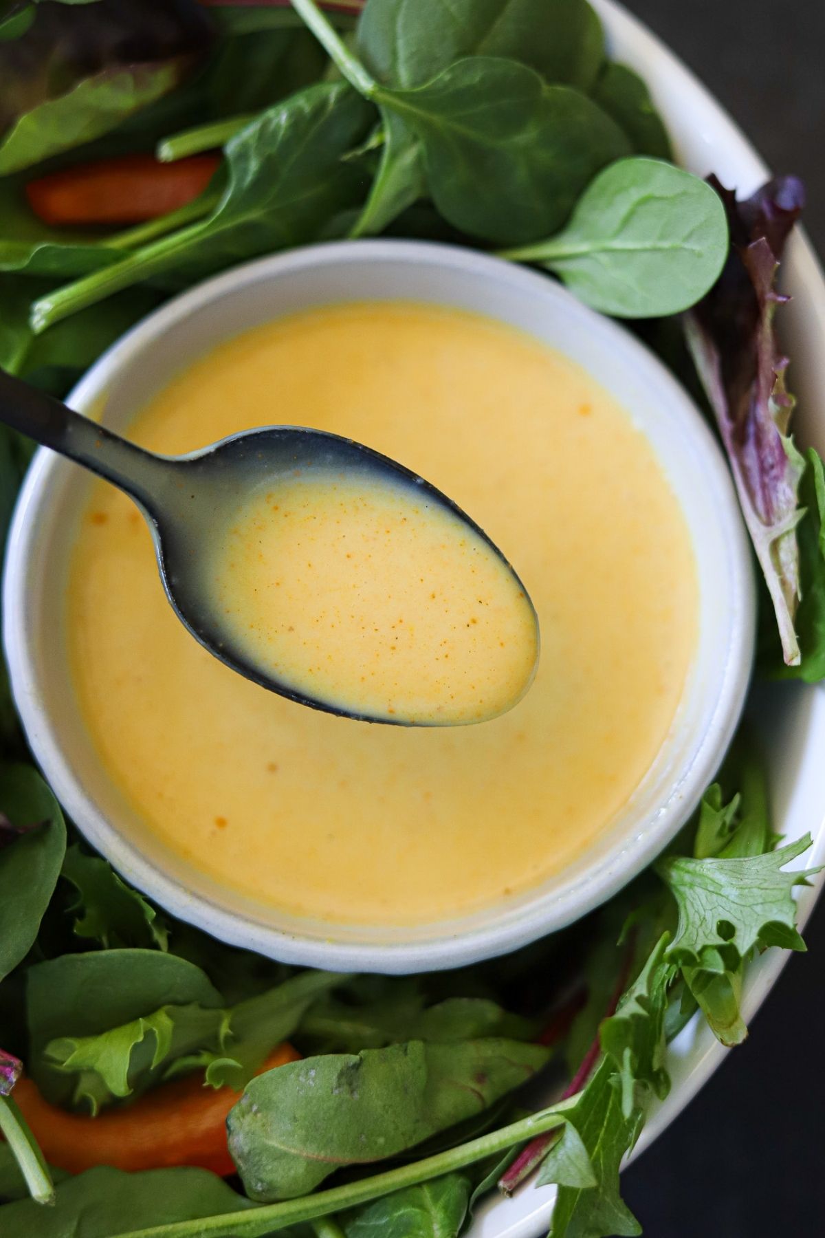 an overhead picture of honey mustard dressing in a bowl of lettuce
