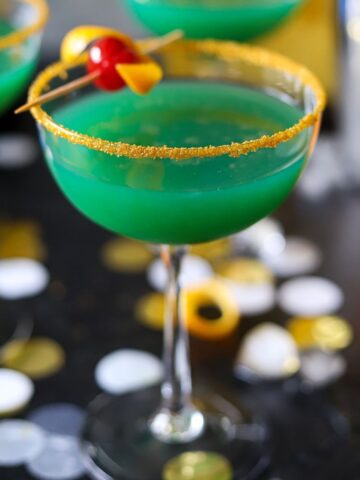 a green cocktail in a gold sugar rimmed coupe glass